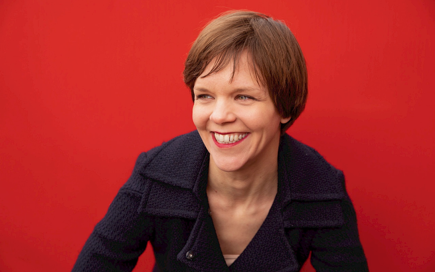 Merav Maroody Portrait Lea Schleiffenbaum, red backround in a black shirt.