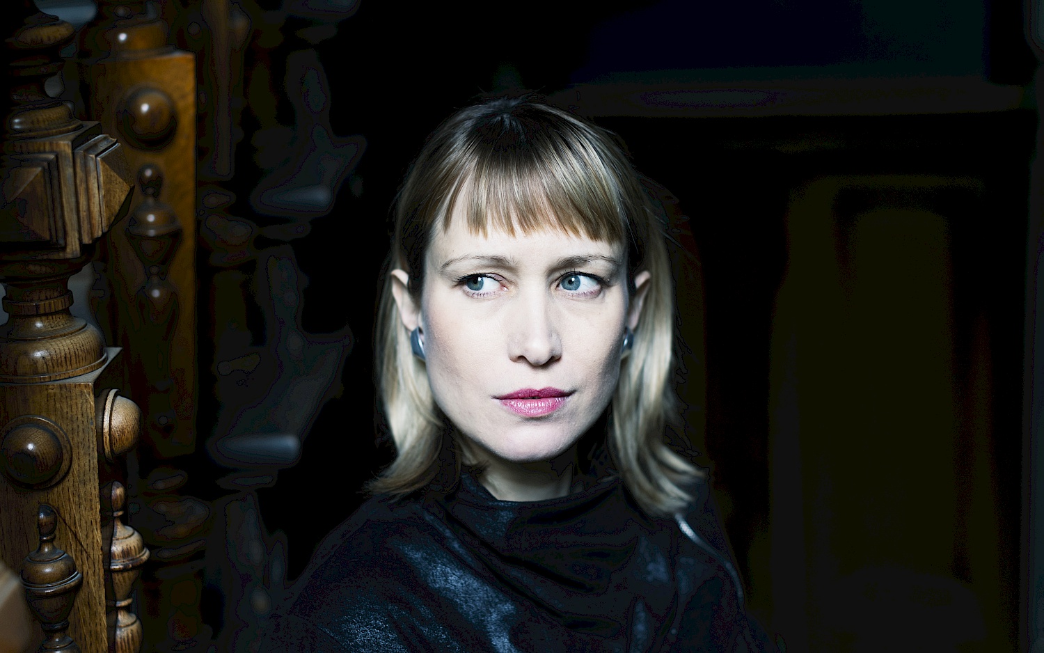 Portraitfoto von Misha Cvijović: beleuchtetes Gesicht vor dunklem Hintergrund, der Blick zur Seite.