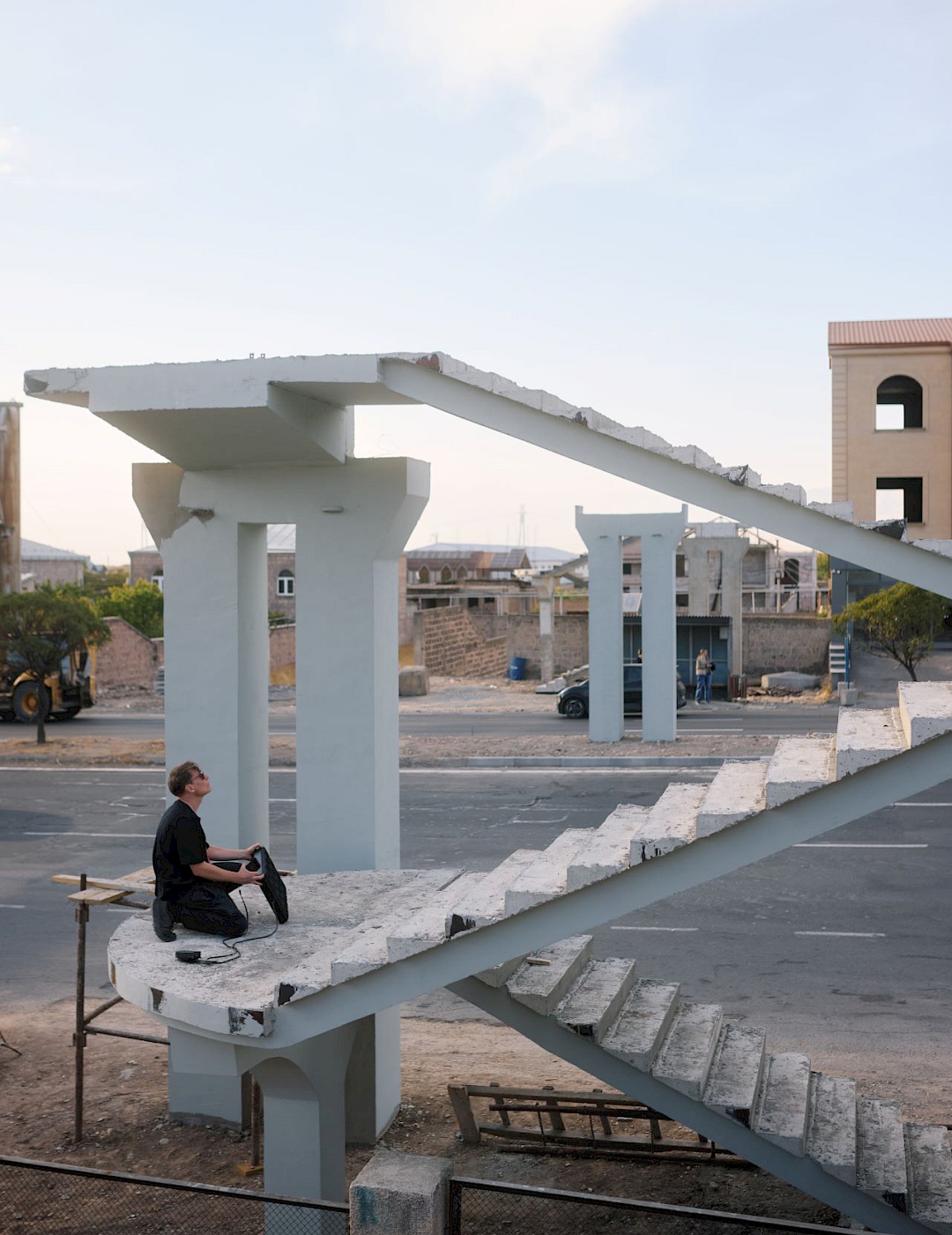 Mitya Iyalin In der weißen Betonruine einer nicht fertig gestellten Brücke sitzt eine schwarz gekleidete Person mit einem elektronischen Musikgerät.