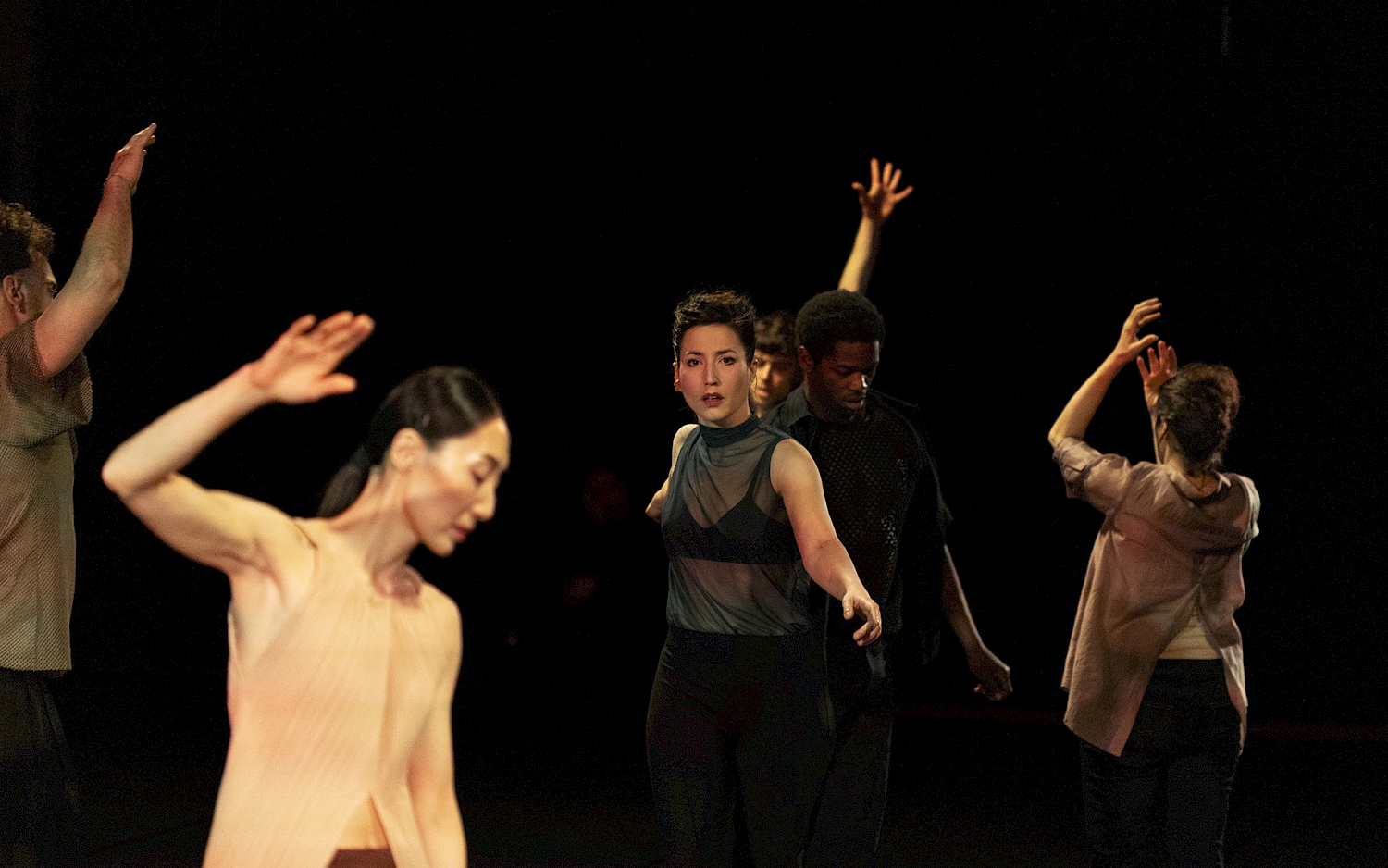Mehrere Performer*innen, tanzend vor schwarzem Hintergrund