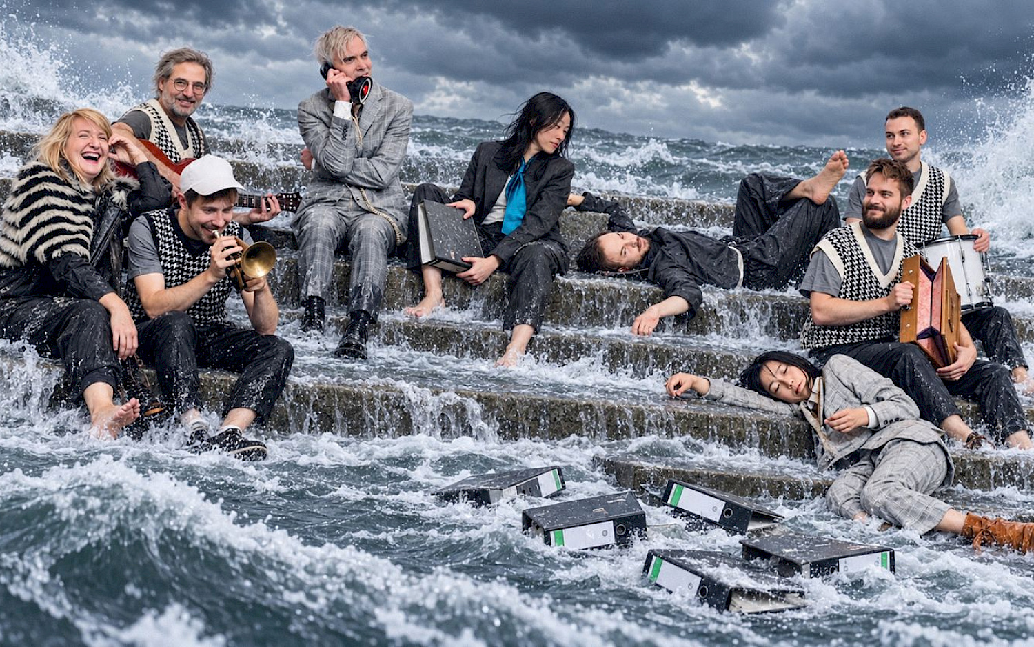 Dieter Hartwig / KI-Bearbeitung NatN Several people, dressed in office attire and some holding musical instruments, sit amidst rushing water beneath a grey sky. In front of them are office binders.