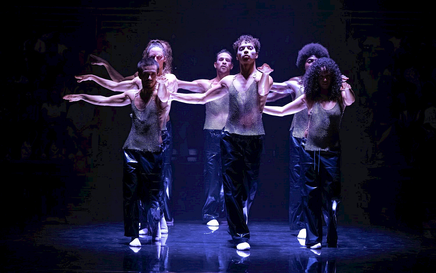 Blandine Soulage Six performers in chainmails on a stage bathed in blue light.