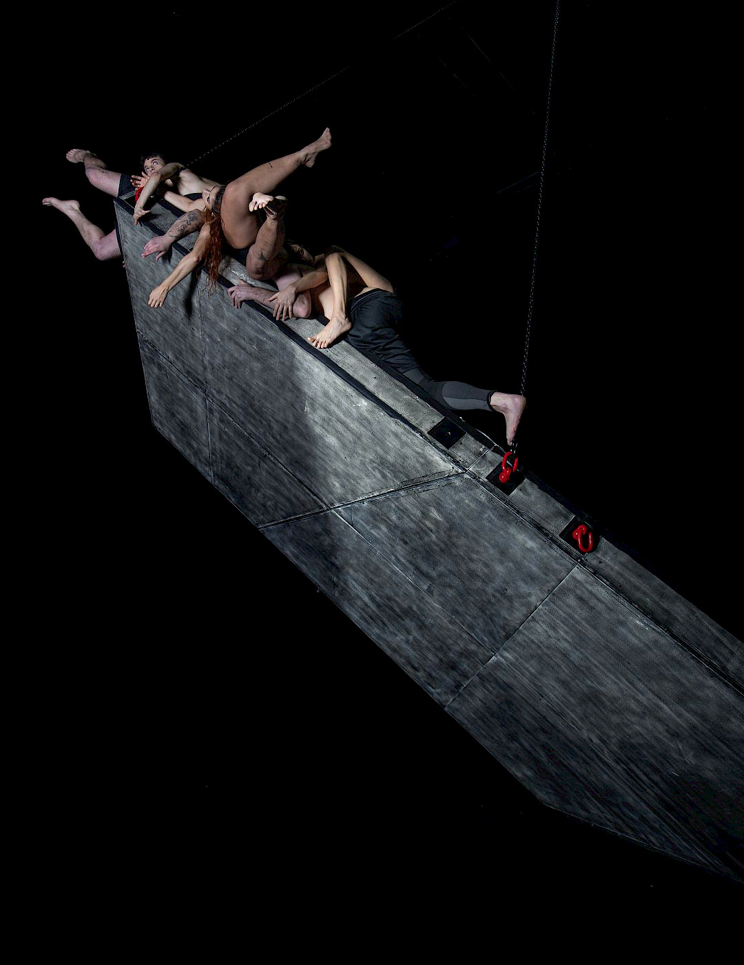 Alipio Padilha Several performers cling to a pointed horn sculpture rising upward.