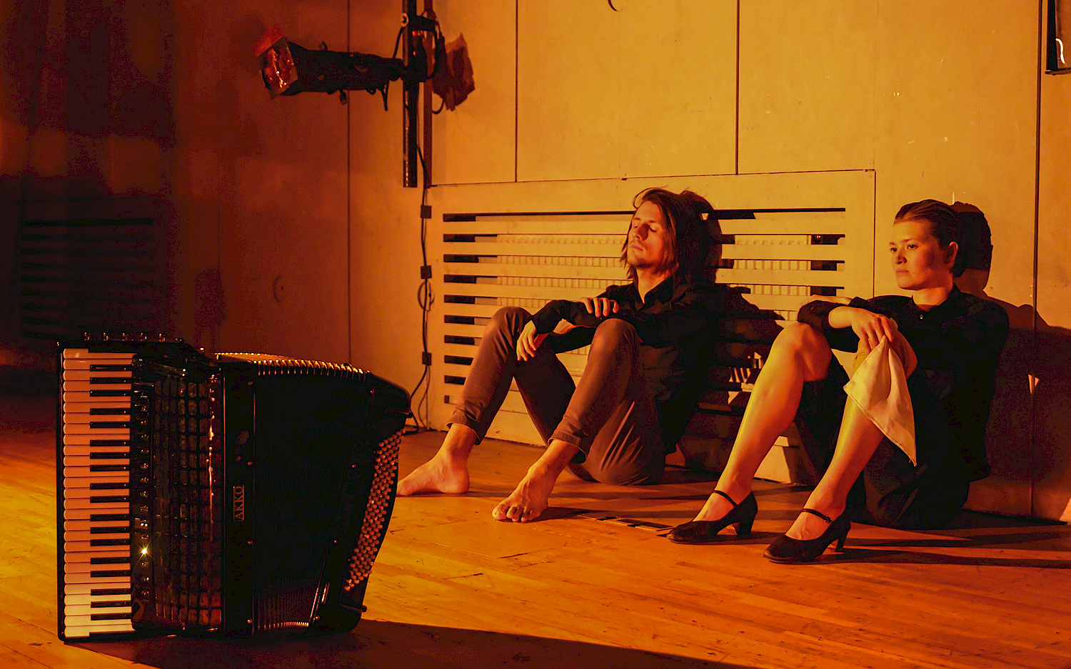Two persons sitting on the floor with an accordeon.