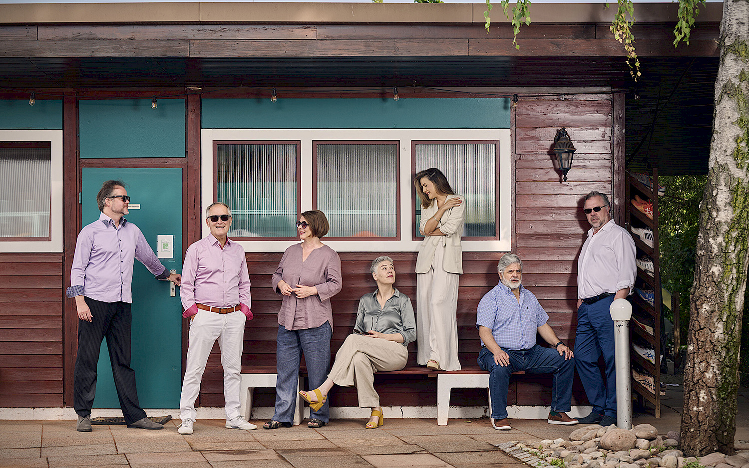 the seven-member ensemble in front of a small house