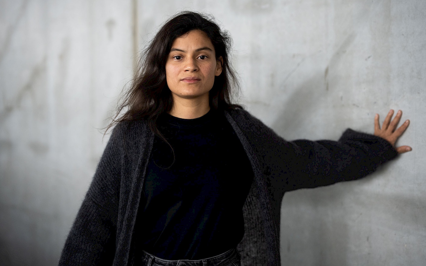 Portrait of Ixchel Mendoza Hernández in front of a grey concrete wall.